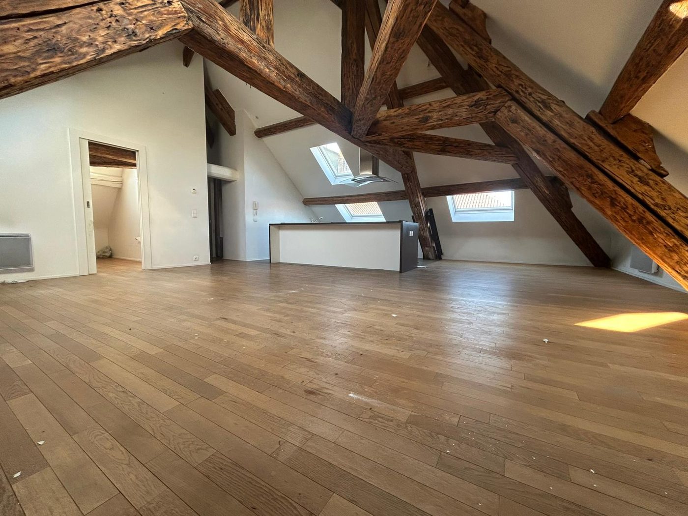 Dernier étage avant rénovation — charpente apparente et volumes bruts