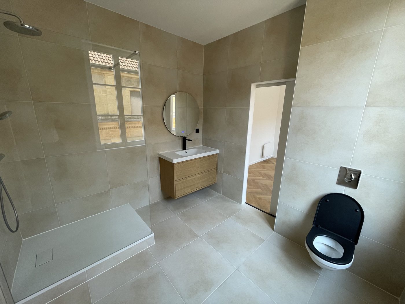 Salle d'eau après rénovation — douche à l'italienne, vasque bois et finitions enduit