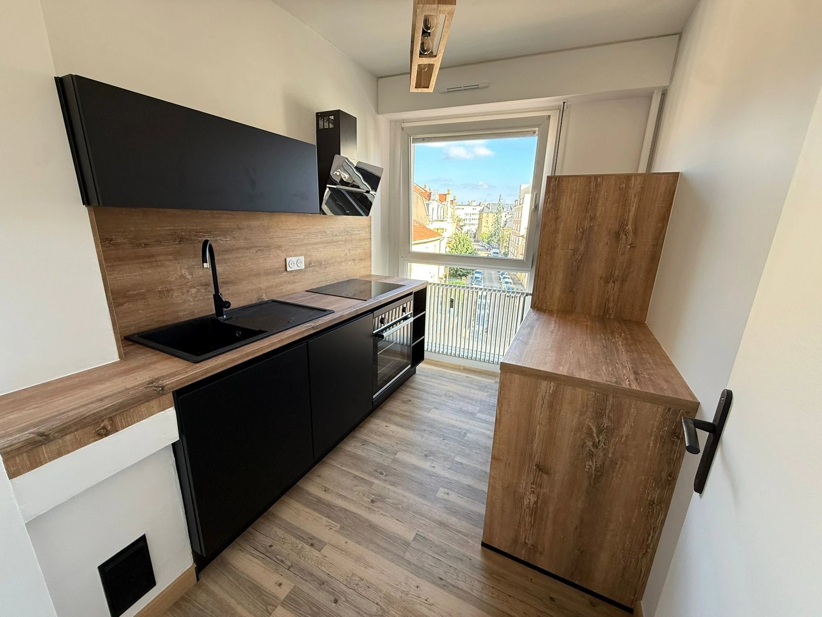 Cuisine équipée moderne — façades noires, plan de travail bois, électroménager intégré