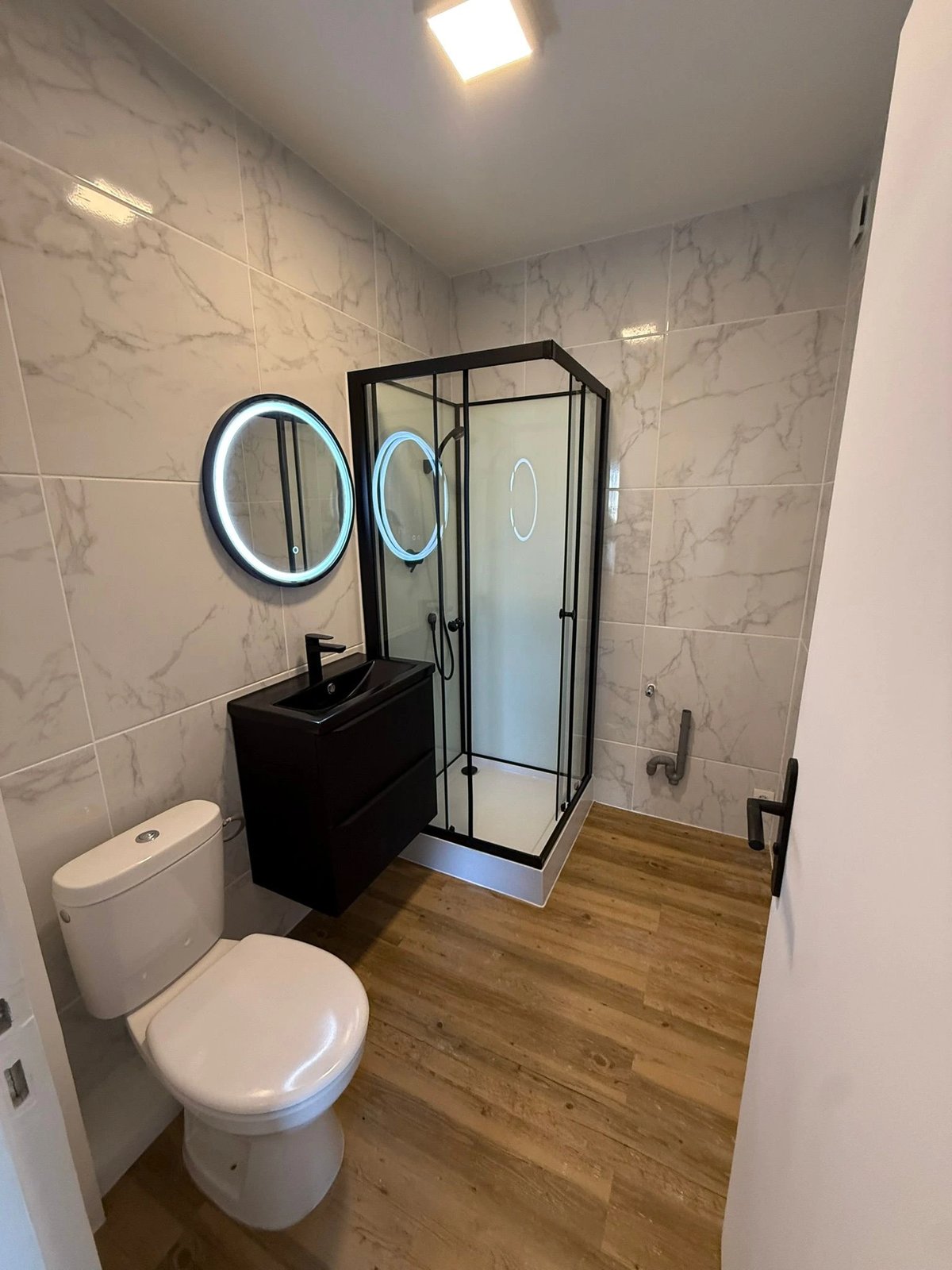 Salle d'eau rénovée — faïence imitation marbre, douche cabine noire, miroir LED