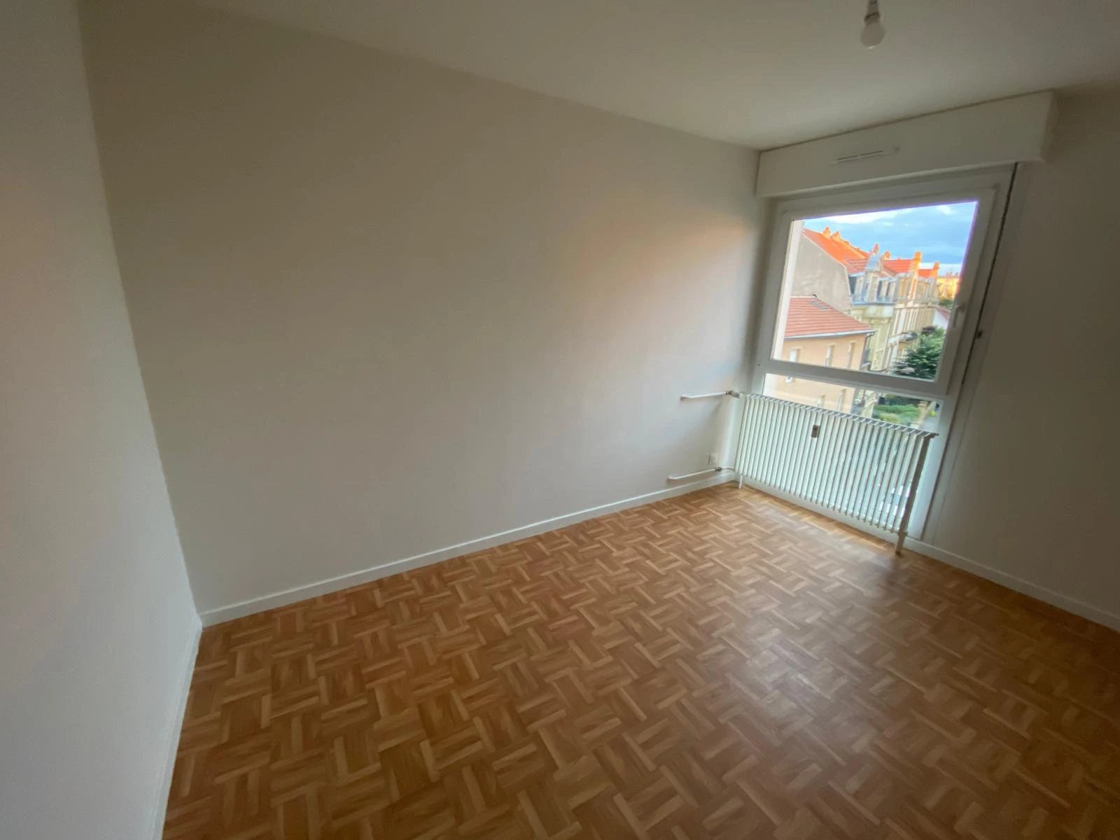 Pièce d'origine — parquet à motifs, fenêtre verticale, mur nu avant agencement cuisine