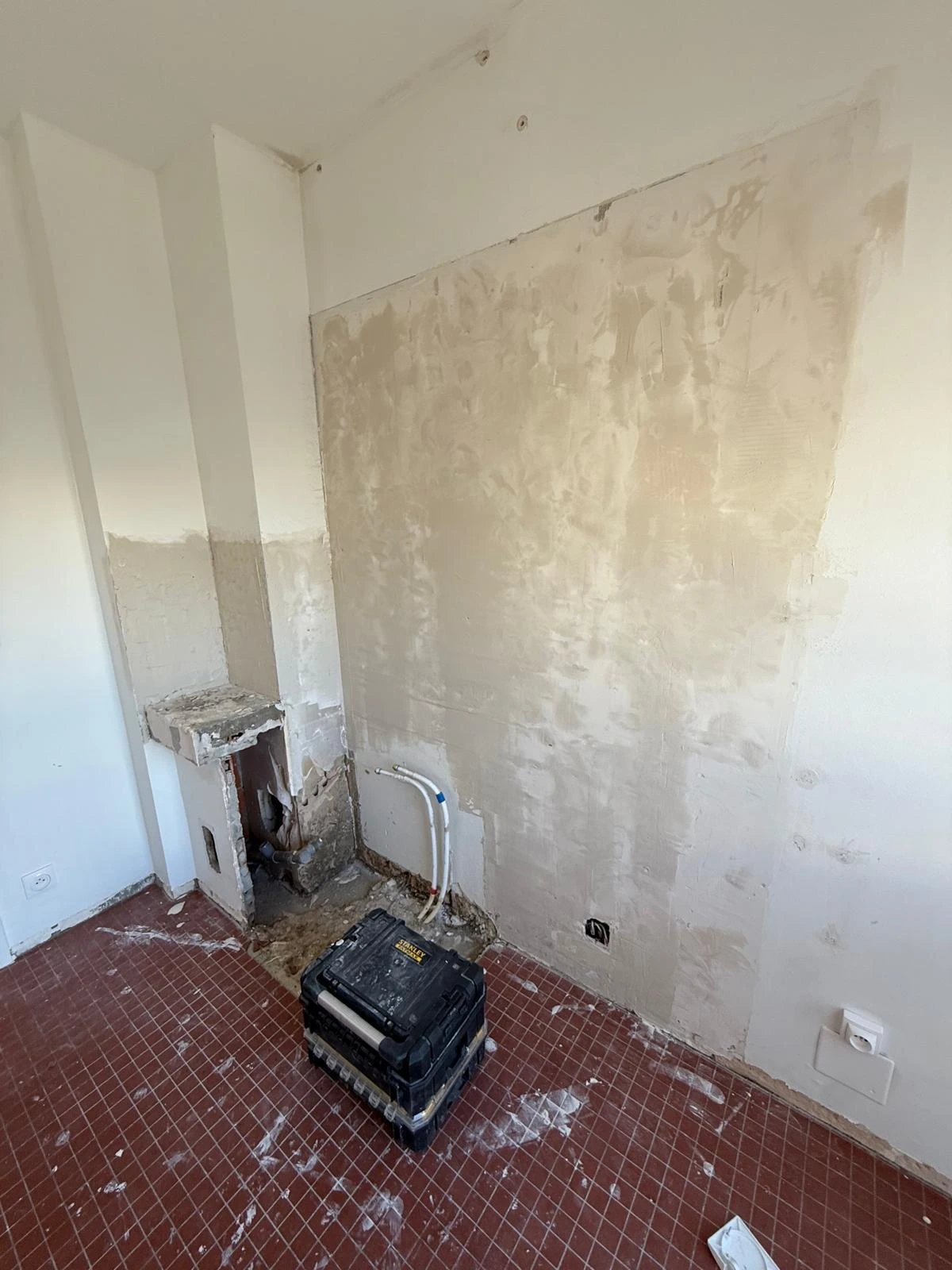 Pièce en chantier — mur béton décapé, futur emplacement de la salle d'eau